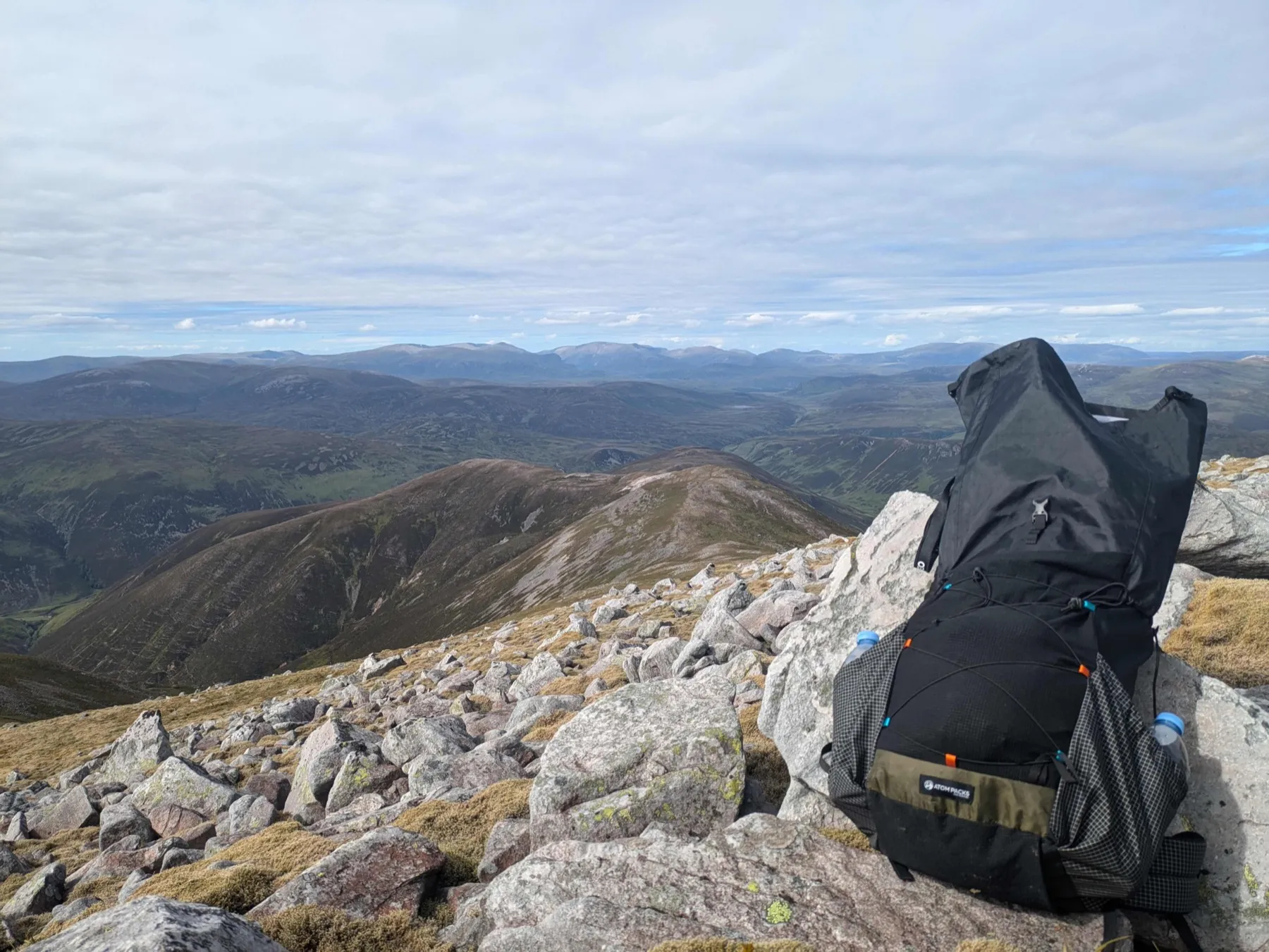 A loaded backpack resting among rocks high in the Scottish mountains