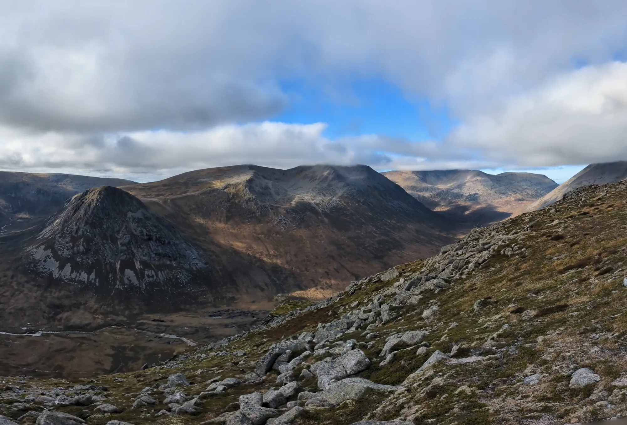 A rocky mountain corrie beneath broken cloud and blue sky
